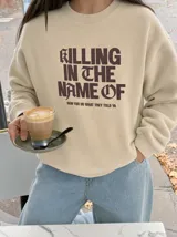 Buzo color beige con estampado frontal en marrón con la frase "Killing in the Name of", cuello redondo, mangas largas y puños y cintura de rib.
