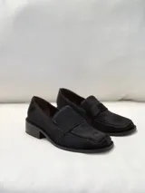 Mocasín de mujer en color negro, confeccionado en cuero con textura de pelo, diseño clásico con banda frontal y suela de taco bajo.
