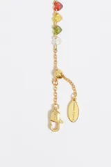 Pulsera de cadena fina dorada de acero inoxidable con una hilera de cristales de vidrio en forma de corazón de múltiples colores. Incluye cierre de mosquetón ajustable y dije de la marca.