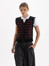 Chaleco negro de largo a la cintura con frente bordado en lentejuelas formando figuras de cerezas. Presenta espalda y sisas tejidas, mangas de organza plisada y cierre frontal con botones grabados.