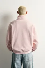 Sudadera de corte regular fit en color rosado, con cuello subido y cierre frontal de cremallera. Presenta manga larga y acabados en rib en puños y ruedo.