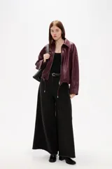Campera de eco-cuero en color bordó, con cuello camisero, cierre frontal con cremallera y cordones ajustables en el ruedo.