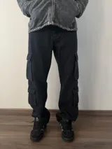 Pantalón tipo jean cargo de corte baggy, color celeste claro, con múltiples bolsillos laterales y cierre frontal.