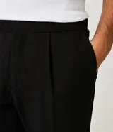 Pantalón masculino de corte slim cropped, confeccionado en viscosa con cintura elástica, bolsillos laterales y traseros, y pliegues delanteros.
