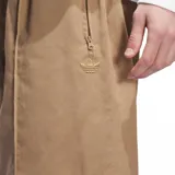 Pantalón Adidas de corte recto y estilo holgado, color beige. Presenta cintura elástica con cordón interno, bolsillos laterales con cierre y detalle de costura vertical frontal (pintuck) con el logo de la marca bordado en la pierna.