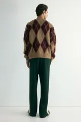 Pantalón deportivo de corte relajado en tejido efecto neopreno, color verde oscuro con franjas laterales en contraste color crema. Presenta cintura elástica con cordón ajustable, bolsillos laterales y traseros, y cierre oculto en el bajo.