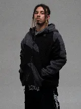 Campera de polar con cierre frontal, diseño de bloques de color en negro y gris oscuro, con capucha y bolsillos laterales.