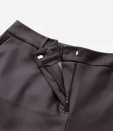 Pantalón de cuero sintético con corte barrel, de tiro alto y pierna ancha con estructura curva. Presenta bolsillos laterales tipo cuchillo y costuras decorativas con pespuntes visibles.