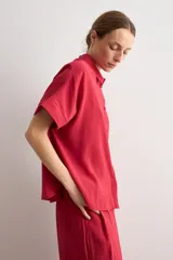 Camisa de manga corta color rojo, de corte holgado, con cuello camisero clásico y cierre frontal abotonado.