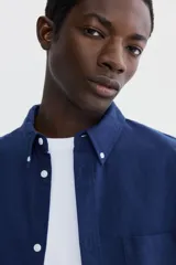 Camisa de manga larga H&M de corte relajado, confeccionada en algodón Oxford azul marino. Cuenta con cuello americano, bolsillo aplicado en el pecho y botones frontales blancos.