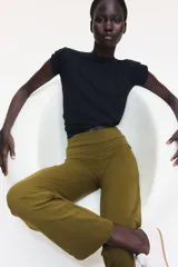 Pantalón de algodón color verde militar, con cintura ancha plegable y perneras de corte recto acampanado.