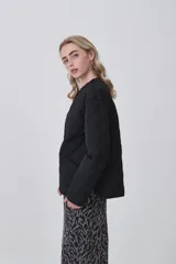 Campera acolchada de diseño capitoneado con patrón de rombos, color negro, de corte holgado, manga larga y cierre frontal con botones a presión.