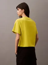 Remera corta color amarillo con cuello redondo, mangas cortas y bolsillo en el pecho con escudo bordado en blanco.