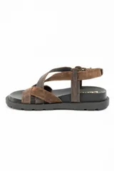 Sandalias de cuero marrón con tiras cruzadas en el empeine, suela chunky negra y hebilla metálica de ajuste en el talón.