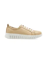 Sneaker de cuero color beige, con suela elevada y estriada de goma blanca, cordones blancos y detalle fruncido elástico en la zona del tobillo.