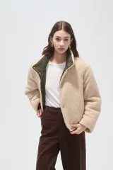 Campera puffer de poliamida color verde militar, con interior y detalles en corderito color crema. Presenta cuello alto, cierre frontal con botones a presión y mangas largas.