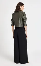 Pantalón sastrero de tiro alto en color negro, con corte ancho y fluido. Presenta pliegues delanteros, cintura estructurada con trabillas y bolsillos laterales. Incluye un cinturón de tela a juego con hebilla metálica ovalada.