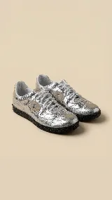 Championes de diseño exclusivo en color plateado metalizado con acabado texturizado. Presentan detalles en gamuza color beige en los laterales, puntera y talón, con suela de goma negra. Incluyen cordones blancos y doble plantilla acolchonada para mayor confort.