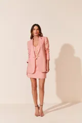 Blazer rosa de lino, con solapas de muesca, cierre frontal con un botón dorado y corte entallado.