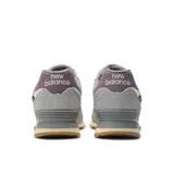 Championes urbanos New Balance 574 de gamuza gris con detalles en lila y blanco. Presentan el logo "N" en los laterales y entresuela ENCAP.