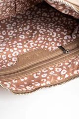 Cartera tipo bandolera de gamuza sintética color bordó, con diseño de flecos largos en la parte inferior y correa ajustable con nudo lateral. Incluye cierre superior y detalle de placa metálica con logo.
