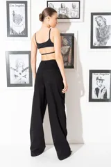 Jean de corte oversize y tiro bajo, color negro, con diseño de argollas metálicas dispuestas verticalmente a lo largo de ambas piernas.