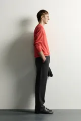 Pantalón negro confeccionado en mezcla de algodón, con cintura elástica, bolsillos frontales y cierre con cremallera y botón.