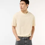 Camiseta de manga corta en color beige, con cuello redondo y diseño de ajuste cómodo y holgado.