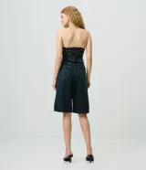 Bermuda long de jean azul con tiro alto, cintura con pasacintos, cierre con botón y cremallera, bolsillos funcionales y pespuntes en contraste.