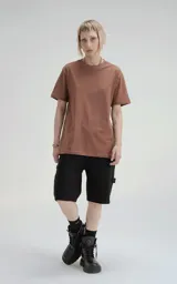 Remera de manga corta y cuello redondo, color marrón (mocca), confeccionada en algodón premium suave. Presenta un calce regular con un recorte distintivo en la espalda.