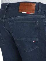 Pantalón de jean Tommy Hilfiger modelo Bleecker, corte slim, color azul oscuro. Confeccionado en tejido denim Power Stretch de mezcla de algodón, con efecto desteñido en las rodillas, estilo de cinco bolsillos y logo bordado en el bolsillo trasero.