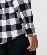 Camisa de manga larga confeccionada en franela de algodón, con estampado de cuadros en rojo y negro, cuello inglés y cierre frontal con botones.