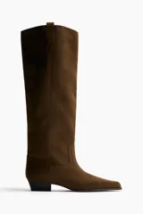 Botas de gamuza color marrón oscuro, con diseño de caña alta hasta la rodilla, punta fina, taco bajo de bloque y costuras decorativas.