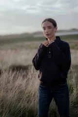 Buzo de punto gris con cuello camisero de denim y cierre frontal parcial con botones metálicos. Presenta mangas largas y un diseño de calce holgado.