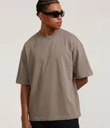 Remera oversize gris de corte holgado, con cuello redondo y mangas cortas de sisa desplazada.