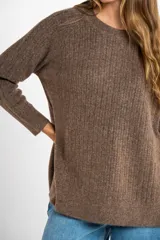 Sweater de punto texturado en color beige, con cuello redondo y mangas largas. Presenta un diseño de tejido acanalado vertical y corte holgado.