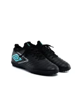 Championes de fútbol Umbro modelo Legacy TF, color negro con detalles en turquesa y gris. Presentan una textura geométrica en el lateral, cuello tipo media para mayor ajuste y suela con tapones pequeños ideales para césped sintético.