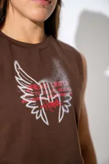 Musculosa crop top de algodón elastizado color marrón, con diseño gráfico frontal de alas y texto en tonos blanco y rosado.