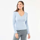Camiseta de pijama de manga larga en color azul claro, confeccionada en tejido de punto calado con textura. Presenta un escote en V con una pequeña tapeta frontal decorada con botones.