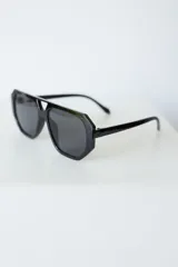 Lentes de sol con armazón de policarbonato negro y cristales tonalidad ámbar, con diseño de puente doble estilo aviador.
