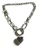Collar de cadena de acero inoxidable con eslabones de diferentes formas y tamaños, que presenta un dije central en forma de corazón de metal pulido colgando de una argolla circular.