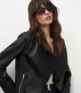 Campera de cuero sintético (PU) color negro, con diseño de solapas delanteras abiertas, mangas largas y corte recto. Presenta detalles de recortes a láser en la superficie.