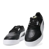 Championes urbanos Puma modelo Shuffle Downtown, de diseño clásico con exterior en cuero sintético negro, franja lateral blanca y suela de goma blanca. Incluye logo de la marca en dorado en el lateral.