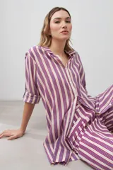 Vestido camisero a rayas verticales fucsia y blanco, con cuello camisero, mangas 3/4 con puños abotonados y cierre frontal con botones.