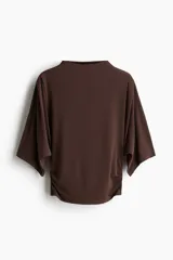 Top de punto elástico color marrón, con cuello alto, mangas al codo de corte amplio y fruncido en los laterales para un efecto drapeado.