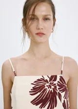 Top de tirantes finos con escote cuadrado, de corte recto y estampado floral en tonos bordó sobre base beige.