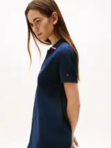 Vestido corto azul marino, tipo chomba, de corte evasé y manga corta. Presenta cuello en V con detalles en blanco y rojo, y logo bordado en la manga.