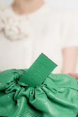Cartera sobre de cuero 100% color verde, de diseño fruncido con cierre superior y etiqueta colgante en combo.