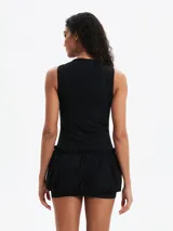 Vestido negro sin mangas, ajustado en la parte superior y con falda corta tipo globo o bombacha fruncida con cordón ajustable en la cintura.