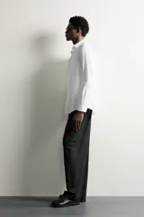 Camisa de vestir blanca de corte slim fit, confeccionada en tejido de algodón con textura estructurada. Cuenta con cuello italiano, mangas largas con puños abotonados y cierre frontal con botonadura.